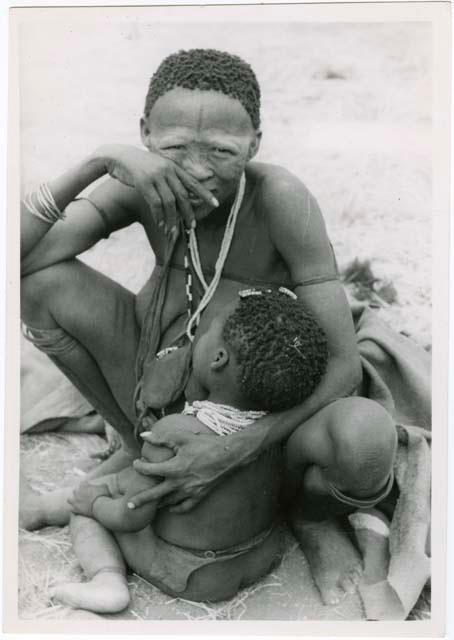 Khuan//a, second wife of Gau, sitting and holding a sleeping child in her lap (print is a cropped image)