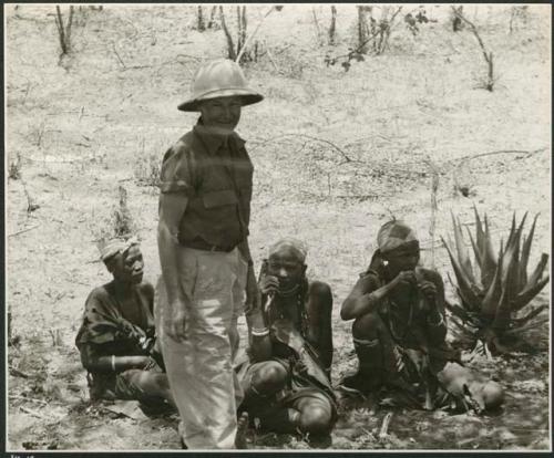 Group of women sitting, with Lorna Marshall standing next to them (print is a cropped image)