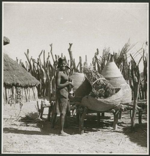 Person sitting next to a storage basket covered with a thatched roof