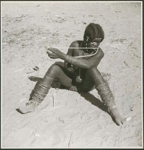 Woman sitting on the ground and playing a musical bow