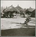 Storage baskets on platforms and covered with thatched roofs, inside kraal