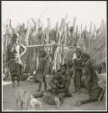 Women and children sitting and standing inside their kraal