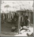 Women sitting and eating in the shade of a thatched roof