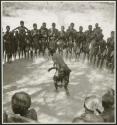 Woman dancing in the center of a circle of women clapping and singing