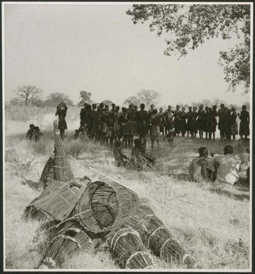 Circle of women dancing, clapping and singing, with fish traps in the foreground