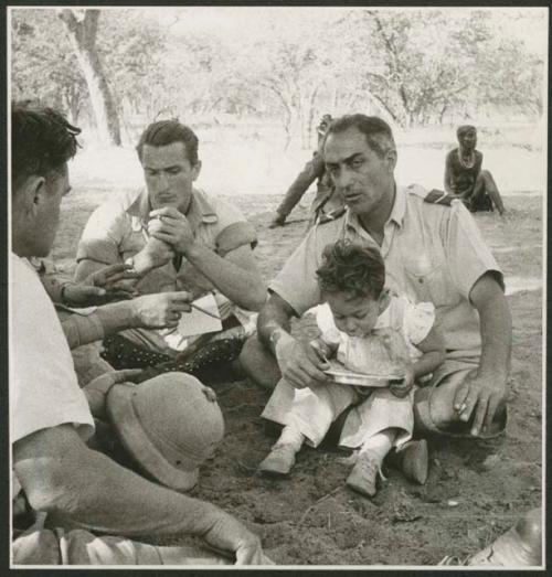 Senhor Simões sitting with his baby on his lap, and Heiner Kretschmar sitting beside him