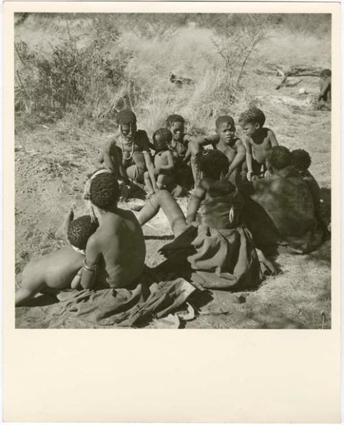 /Naoka (first wife of /Ti!kay) performs a choa ceremony for her daughter, Bau (wife of Tsamgao). N!ai (/Naoka's sister); !Ghia (wife of ≠Gao), and Goishay (mother of /Naoka and N!ai) are seated with their backs to the camera watching