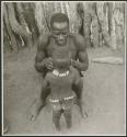 Man sitting, with a child standing in front of him