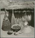 Fish traps, baskets and food in front of a hut