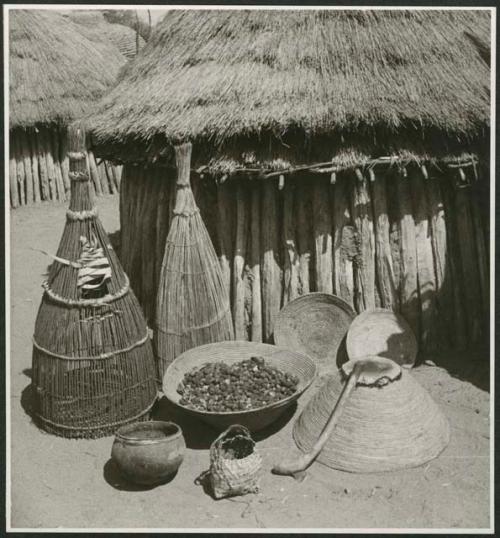 Fish traps, baskets and food in front of a hut