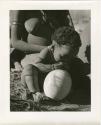 Baby sitting next to an ostrich eggshell (print is a cropped image)