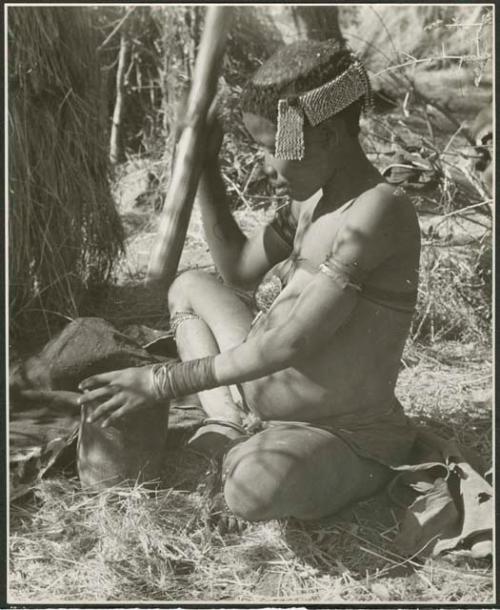 //Kushay ("Gao Helmet's" second wife) pounding with mortar and pestle, wearing ornaments and ostrich eggshell beads on her head (print is a cropped image)