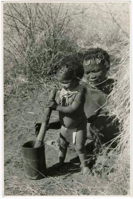 !Ungka (≠Toma's sister) and her daughter, Sa≠gai, who is playing with a mortar and pestle (print is a cropped image)