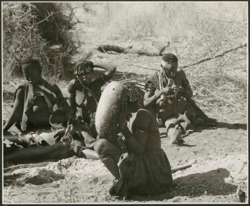 Group of Ju/'hoansi including !Ungka, //Kushay, //Kushay's sister, /Qui's wives, and other unidentified people; woman holds a //guashi in the foreground (print is a cropped image)