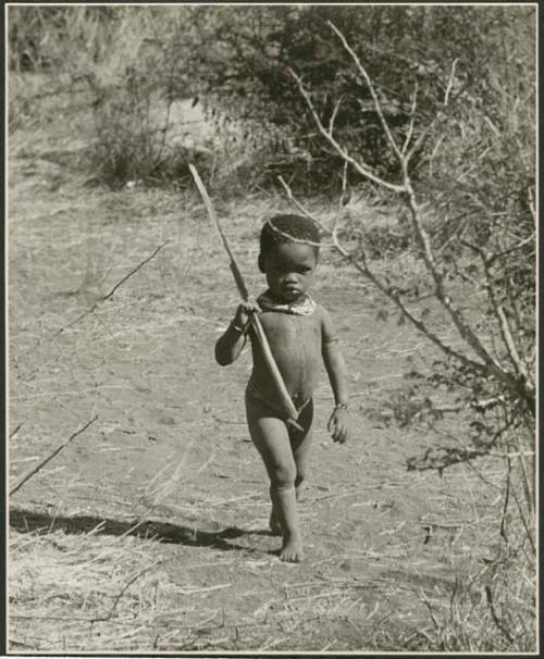 Boy walking and carrying a stick (print is a cropped image)