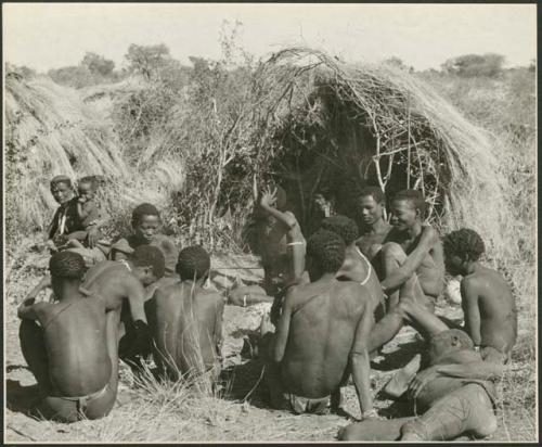 Group of Ju/'hoansi telling stories including "Lame ≠Gao" seen from behind, ≠Gao (Khwo//o's-/Gasa's husband), "Gao Medicine," an unidentified person, ≠Toma, !Naishi, "Old Xama" holding a child, "Gao Helmet," "Old Demi" lying down, "Crooked /Qui," Gao (Debe's son, Zuma's husband), ≠Toma (!Naishi's son), and Zuma (Gao's wife)  (print is a cropped image)