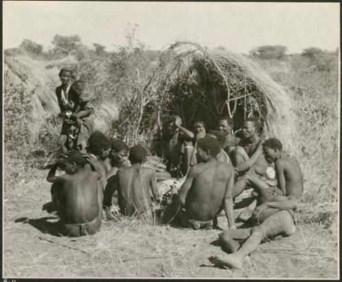 Group of Ju/'hoansi telling stories including "Lame ≠Gao" seen from behind, ≠Gao (Khwo//o's-/Gasa's husband), "Gao Medicine," an unidentified person, ≠Toma, !Naishi, "Old Xama" holding a child, "Gao Helmet," "Old Demi" lying down, "Crooked /Qui," Gao (Debe's son, Zuma's husband), ≠Toma (!Naishi's son), and Zuma (Gao's wife) (print is a cropped image)