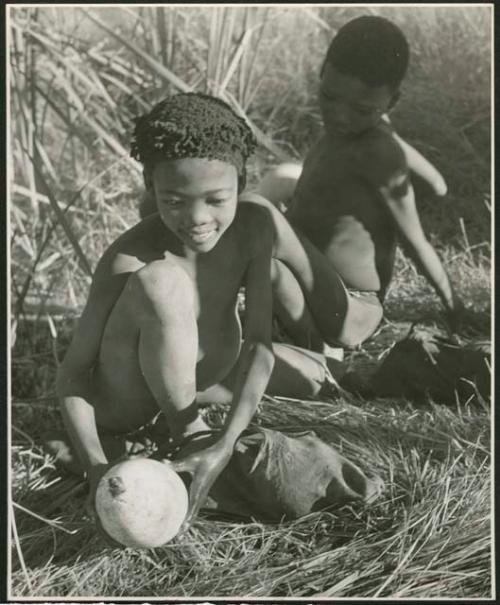 /Qui (son of "/Gao Music") holding an ostrich eggshell containing water, with an unidentified boy behind him (print is a cropped image)