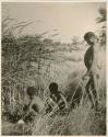 "≠Gao Lame" standing, and two unidentified boys sitting, at the edge of a waterhole (print is a cropped image)