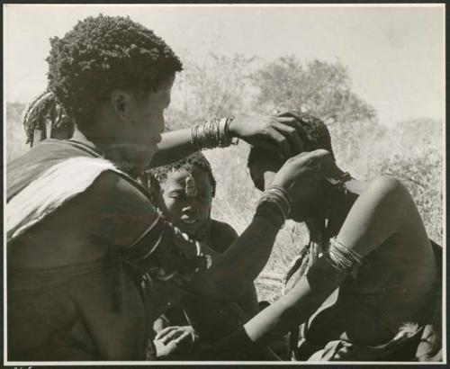 Woman fixing another woman's earring (print is a cropped image)