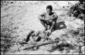 Oukwane sitting, with his possessions laid out on the ground in front of him