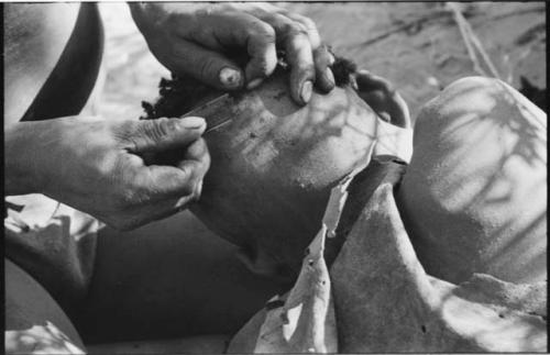 !Gai cutting another person's hair with a razor blade, close-up