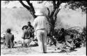 People sitting under a tree, and Laurence Marshall walking toward a group of expedition members