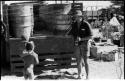 Boy carrying N!whakwe on his shoulders toward Casper Kruger standing at the back of an expedition truck (GMC)