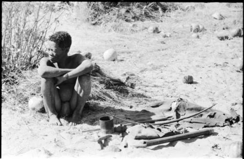 Oukwane sitting, with his possessions on the ground next to him