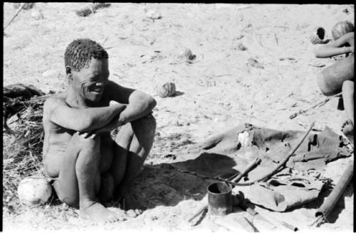 Oukwane sitting, with his possessions on the ground next to him