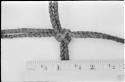 Knot in carrying net, close-up, with a ruler for measurement