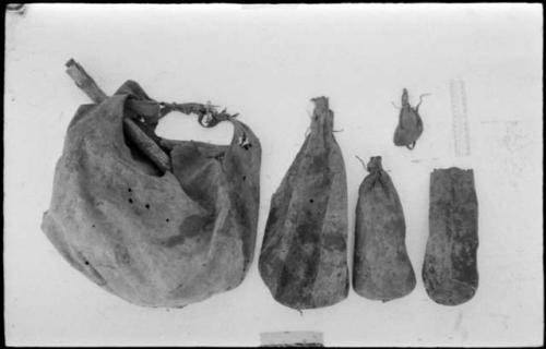 Five skin bags used to contain /Twikwe's possessions, including a ≠dobe, made of steenbok skin, with a scraper in it, and 4 /twam of different sizes, with a ruler for measurement