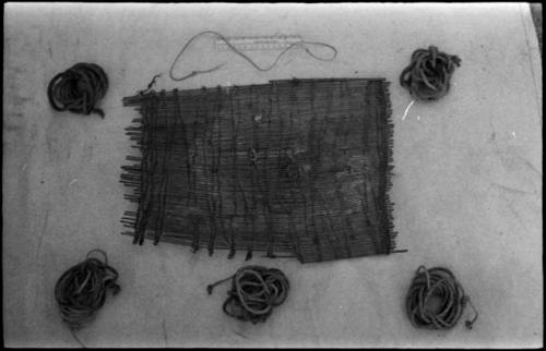 /Twikwe's possessions, including a sieve woven with strips of bark, five bundles of cord of the size for snare, and a fine cord made of sinew for tying around her stomach to keep it tight and reduce hunger pangs, with a ruler for measurement