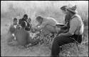 Oukwane and other people sitting and talking to William Donnellan and Elizabeth Marshall Thomas, with Wilhelm Camm interpreting. Oukwane is naming the internal parts of an animal.