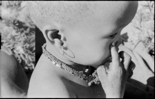 N!whakwe wearing an earring, close-up