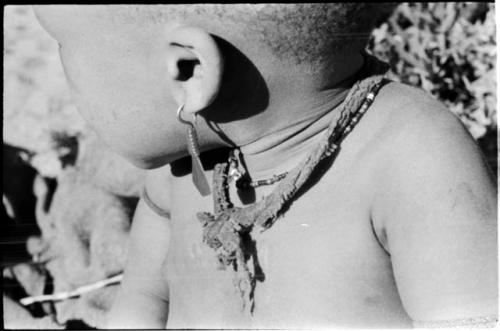 N!whakwe wearing a necklace and earring, close-up