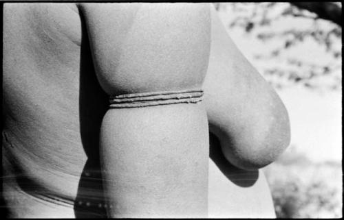 Woman wearing thong bracelets on her upper arm, close-up