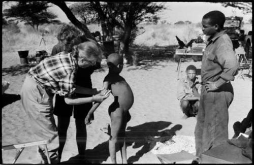 Child having their skin color documented by Lorna Marshall, with Kernel Ledimo watching