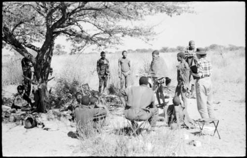 Members of a visiting band from Okwa sitting and standing under a tree, with Kernel Ledimo and Lorna Marshall