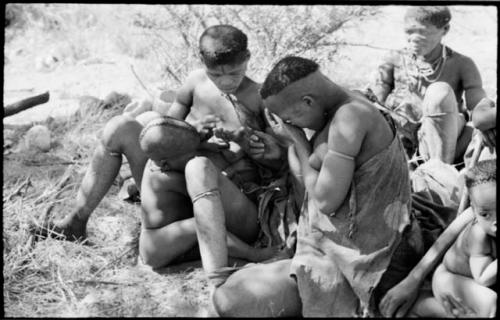 Woman nursing her child, with an older woman in the background, members of the band visiting from Okwa