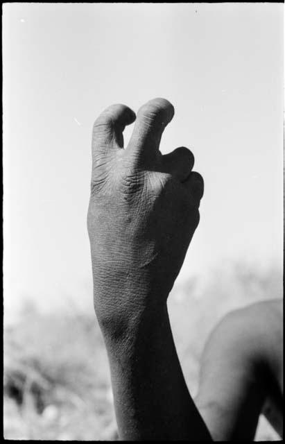 Person demonstrating the hunting hand signal for a hartebeest, showing the horns bent forward