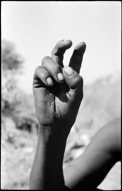 Person demonstrating the hunting hand signal for a  hartebeest, seen from the front