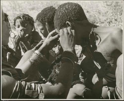 Woman fixing another woman's earring (print is a cropped image)