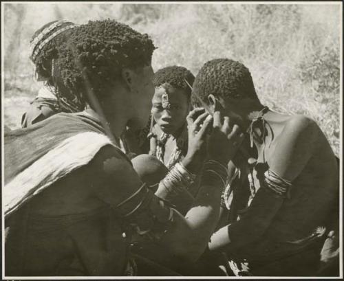 Woman fixing another woman's earring (print is a cropped image)