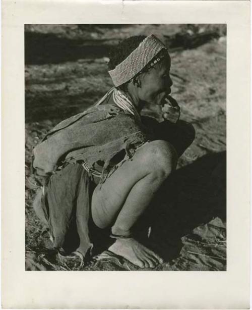 /Naoka, wife of "Gao Medicine," squatting, and wearing an ostrich eggshell headband (print is a cropped image)