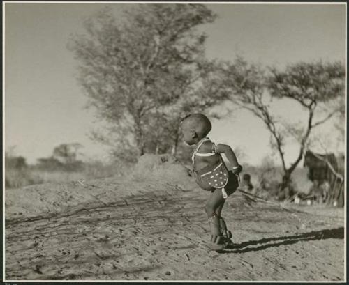 /Gaishay wearing beads, a bag, and dance rattles; he is playing Bah n≠aq’u (the stick throwing game) (print is a cropped image)