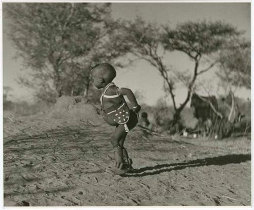 /Gaishay wearing beads, a bag, and dance rattles; he is playing Bah n≠aq’u (the stick throwing game) (print is a cropped image)