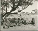 Group of men sitting under a tree watching the oracle disks being thrown (print is a cropped image)