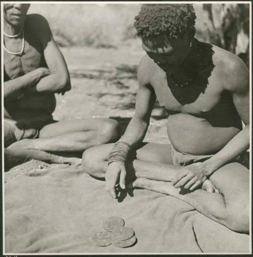 Man sitting and contemplating oracle disks (print is a cropped image)