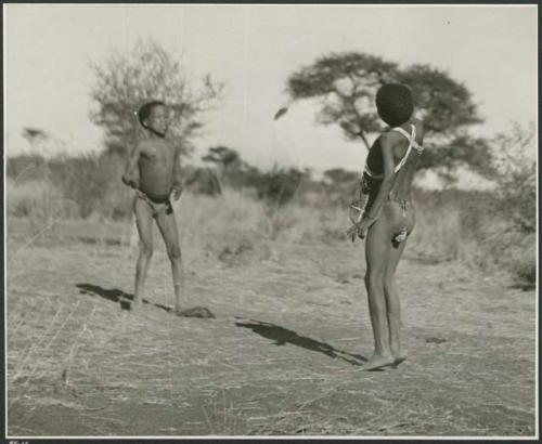 Two boys tossing a djani (helicopter toy / winged toy made from a hollow reed)  (print is a cropped image)